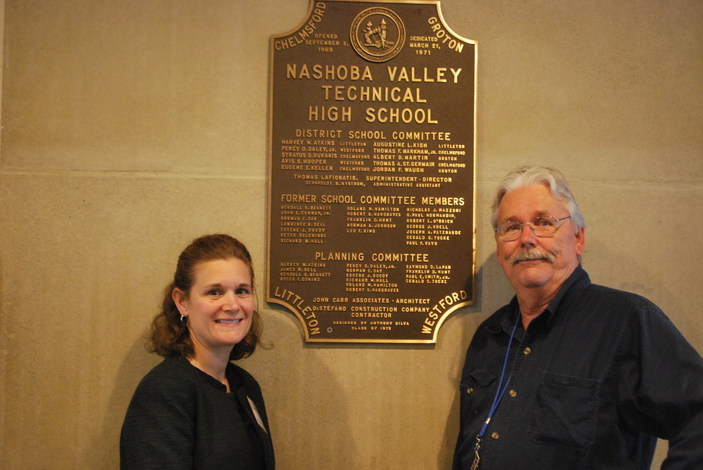 Nashoba Tech Superintendent Denise Pigeon and School Committee Chairman Charlie Ellis of Littleton stand in front of the original plaque dedicating the school in 1969. Ellis, a member of the first graduating class at Nashoba Tech in 1971, now sits on the committee.